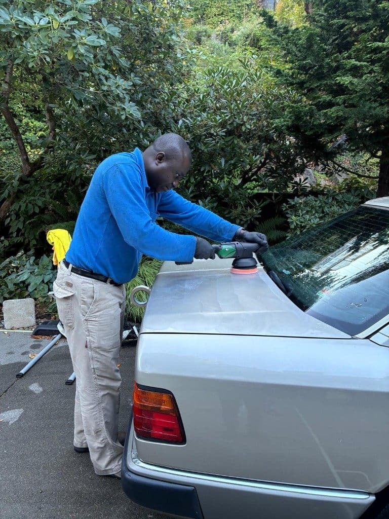 Theo polishing a silver car with a buffer during a mobile detailing appointment